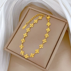 Golden titanium steel four-leaf clover chain bracelet on elegant silk background