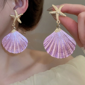 Detail of starfish studs and glossy purple shell pendants on a worn model