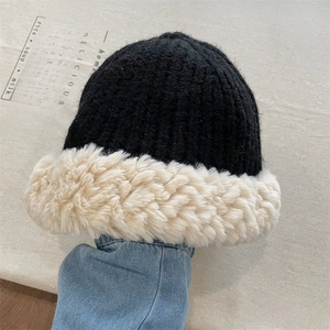 Close-up of black knitted beanie featuring thick cream faux fur trim on the brim