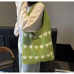 Detalle del bolso de hombro de punto verde con corazones blancos y textura tejida suave