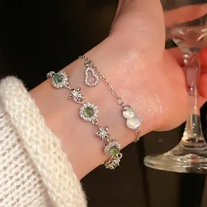 Elegant layered zircon flower bracelet set with green gemstones on a female wrist