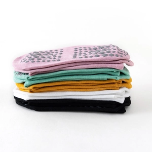 Stack of five colorful non-slip cotton yoga socks with grey silicone grip dots on the soles