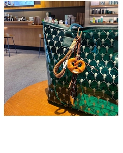 Close-up of translucent dark green tote with fish scale pattern and pretzel keychain charm