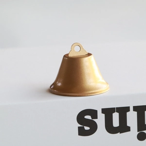 Close-up of a small golden metal bell with matte finish for Christmas DIY ornaments