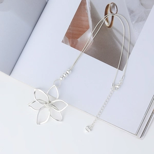 Detailed view of large silver flower pendant with snake chain and heart-shaped charm tag