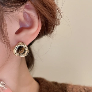 Close-up of golden spiral texture earrings with vintage faux tiger eye agate on model
