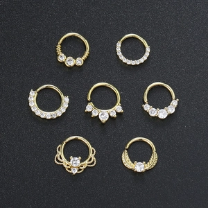 Macro detail of seven assorted gold nose rings with micro-set cubic zirconia on black background