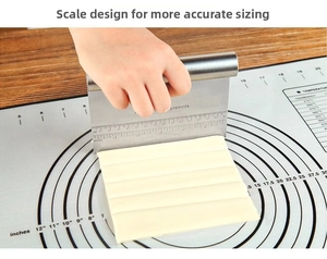 Close-up of stainless steel bench scraper with measurement markings cutting dough