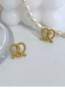 Macro detail of gold twisted bow stud earrings in 925 silver with elegant pearl accents