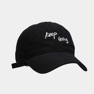 Detailed view of Keep Going embroidery on black cotton baseball cap with adjustable strap
