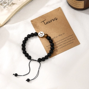 Detail of handmade Taurus zodiac bracelet with black matte beads and adjustable cord