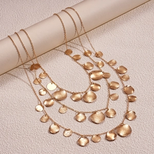 Detail of layered gold necklace with hammer-textured round pendants on minimalist display