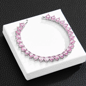 Detailed view of silver tennis chain with heart-shaped pink zircon stones on display stand