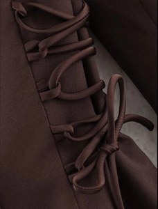 Detail of side lace-up design and bow knot on a coffee-colored satin blazer