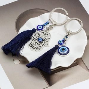 Detail of Hamsa hand and Evil Eye charms with blue tassels on a white ceramic plate