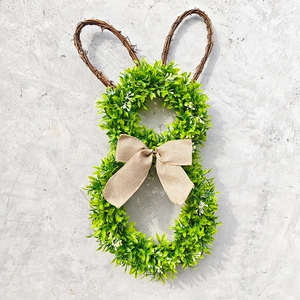 Detail of bunny-shaped Easter wreath with faux green leaves and a rustic burlap bow