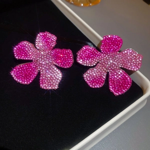 Macro shot of pink floral stud earrings with sparkling crystals in a black jewelry box