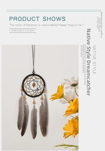 Close-up of bohemian dreamcatcher with black weave, gold beads, and grey feathers