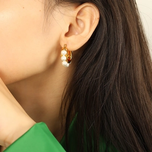 Elegant gold hoop earrings with triple pearls shown on a model for a chic French style