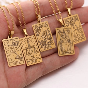 Close-up of five golden tarot card necklaces being held in a hand for size comparison