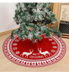 Macro detail of red knitted Christmas tree skirt with white reindeer and Merry Christmas text