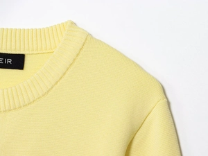 Close-up of the round neckline and EIR brand label on a yellow knit cardigan