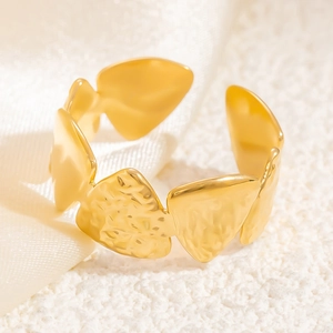 Close-up of gold hollow leaf open ring with hammered texture on white silk fabric