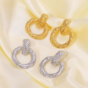 Boucles d'oreilles nœuds torsadés rétro en or et argent sur un tissu en soie élégant