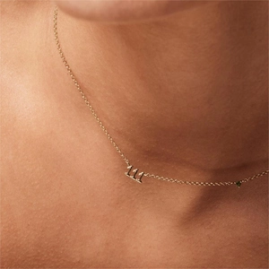 Close-up of gold 111 angel number necklace with a green gemstone on a woman's neck