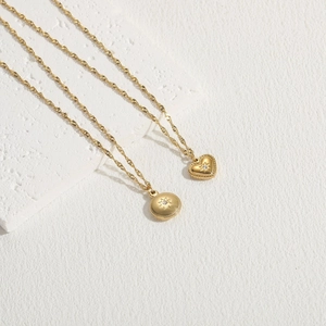 Close-up of gold twist chain necklaces featuring star-engraved heart and round pendants