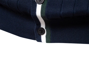 Dettaglio del cardigan in maglia blu scuro con strisce verde-bianco e bottone nero