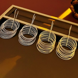 Detailed view of layered circular drop earrings in gold and silver finishes on display