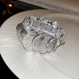 Detail of silver textured metal elastic bracelet with hammered coin link design