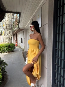 Detail of a bright yellow strapless maxi dress with shirred bodice and high side slit