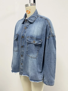 Detail of vintage washed blue denim shirt showing front flap pockets and frayed raw hem edges