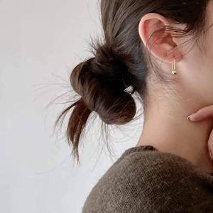 Close-up of minimalist gold beaded drop earrings worn on a model in a lifestyle setting