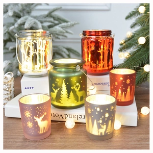 Close-up of Christmas glass candle holders with reindeer forest silhouettes and warm light