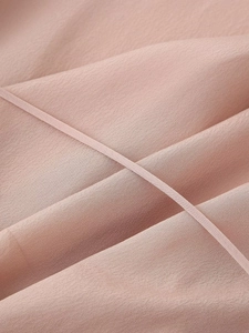 Dettaglio del tessuto in raso di seta rosa elegante con texture liscia e cordoncino abbinato