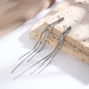 Detail of silver tassel earrings with sparkling rhinestones on stone background
