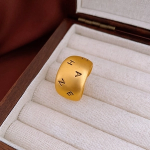 Bague large dorée mate avec gravure de lettres HANE présentée dans un écrin en bois