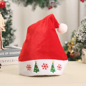 Detail of red velvet Christmas hat featuring white plush cuff with festive tree embroidery