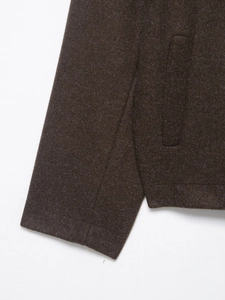 Détail de la veste en laine marron foncé montrant les coutures précises au poignet et poche