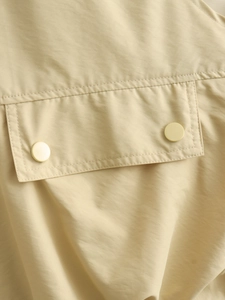 Détail du gilet kaki clair avec poches à rabat boutonnées et finitions de couture