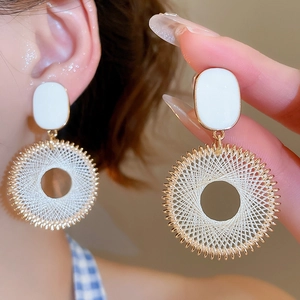 Close-up of asymmetrical white oil-drop heart earrings worn on ear with golden details