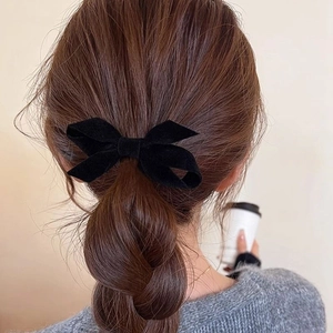 Elegant black velvet bow hair clip for women, styled on a braided hairstyle for a chic look