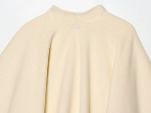 Close-up of cream wool blend coat showing neck detail and single button fastening