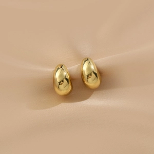 Vue détaillée de boucles d'oreilles dorées en goutte d'eau sur velours rose