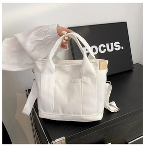 Close-up of white canvas tote bag with sturdy top handles and adjustable shoulder strap