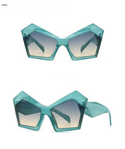 Detail view of cyan irregular polygon sunglasses with blue gradient lenses on white backdrop