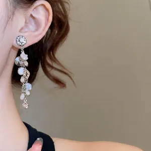 Eleganti orecchini a fiore dorati con cristalli e perle indossati da una modella